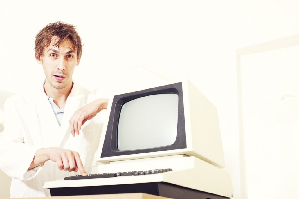 A clueless person in a lab coat typing on an old computer